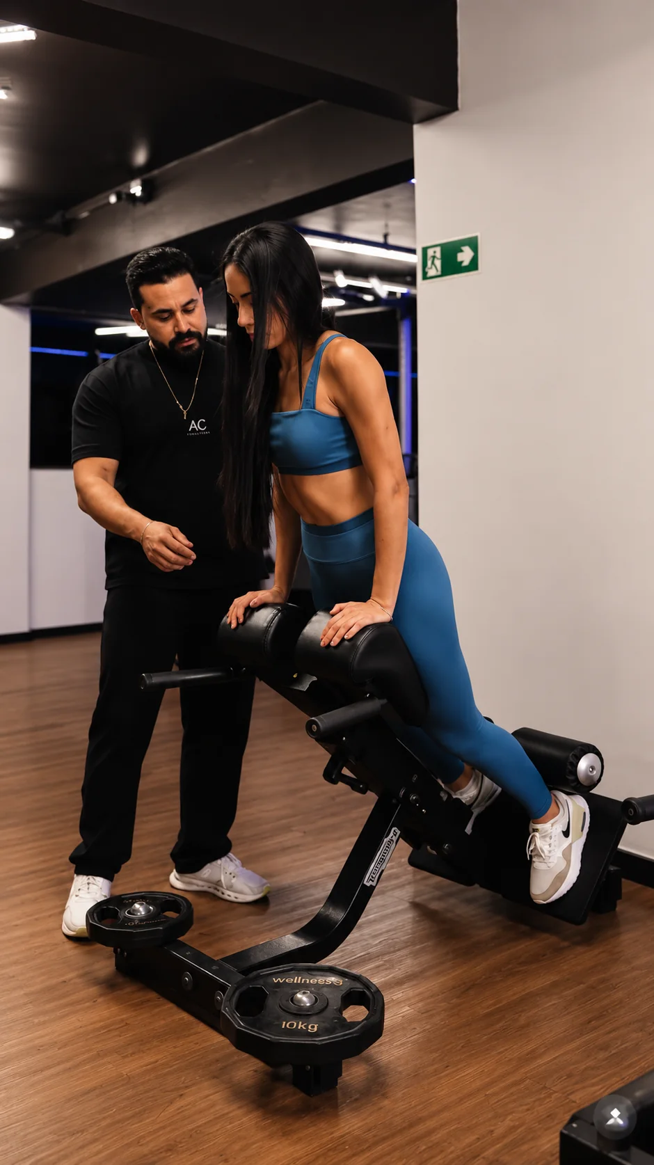 André orientando uma aluna durante um exercício na academia